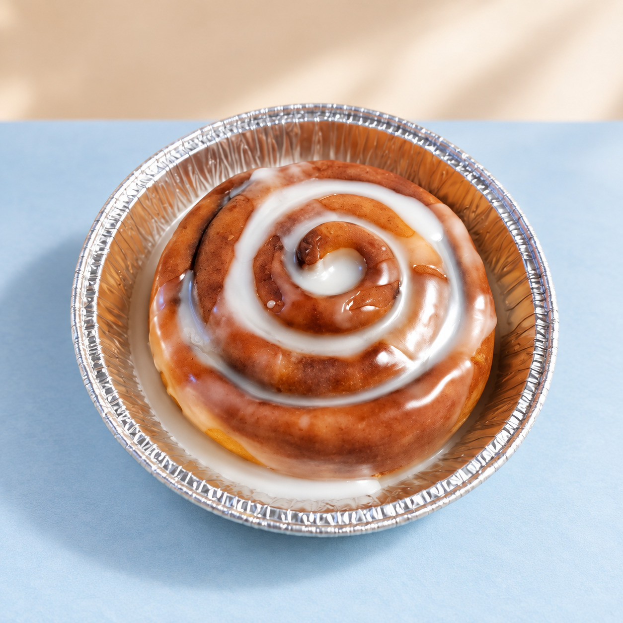 Glazed cinnamon-roll candle in a foil tin