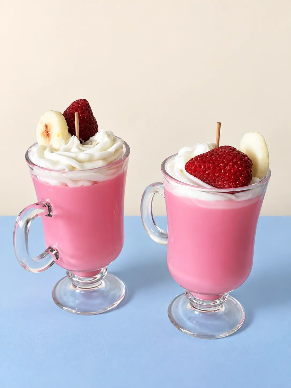 Two pink drink candles in clear handled mugs