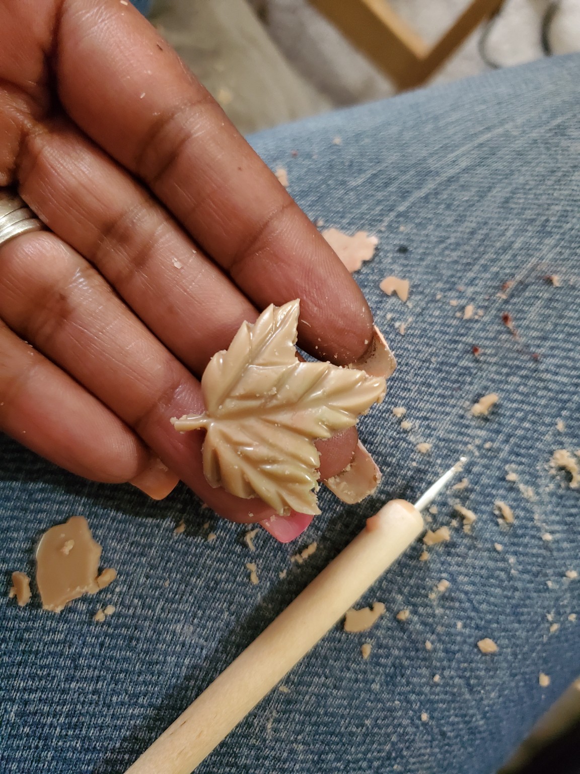 A small wax leaf being carefully carved by hand